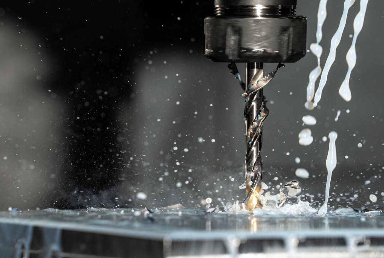 Services High-speed close-up of CNC drill bit in action with water splash for lubrication.